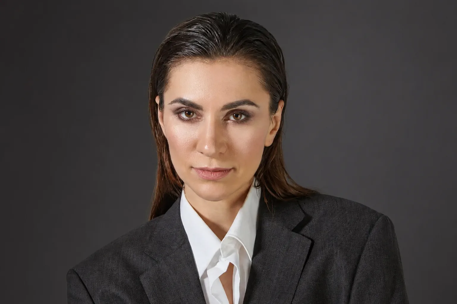 Kobieta w eleganckim szarym garniturze i białej koszuli.