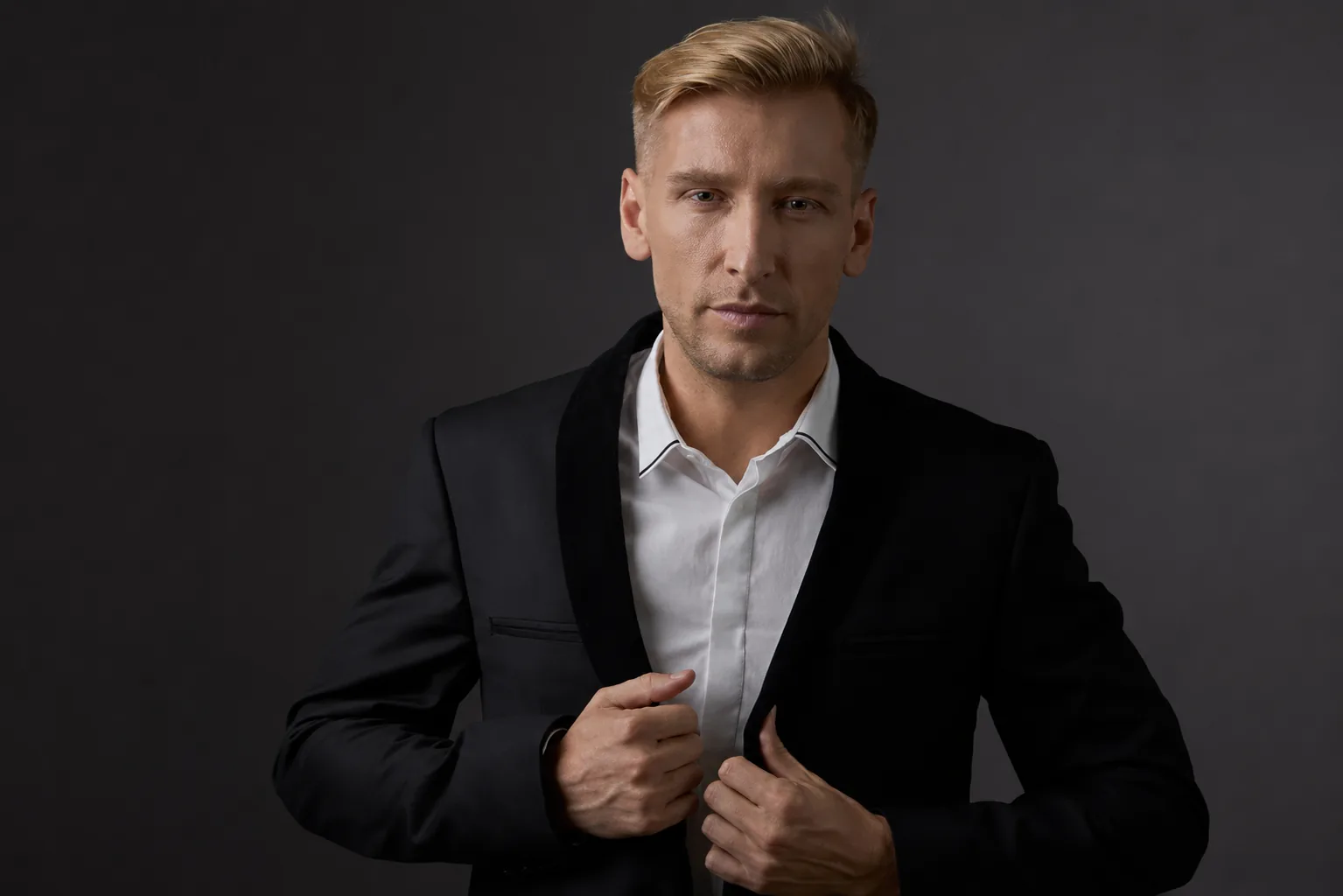 Mężczyzna w czarnej marynarce i białej koszuli.